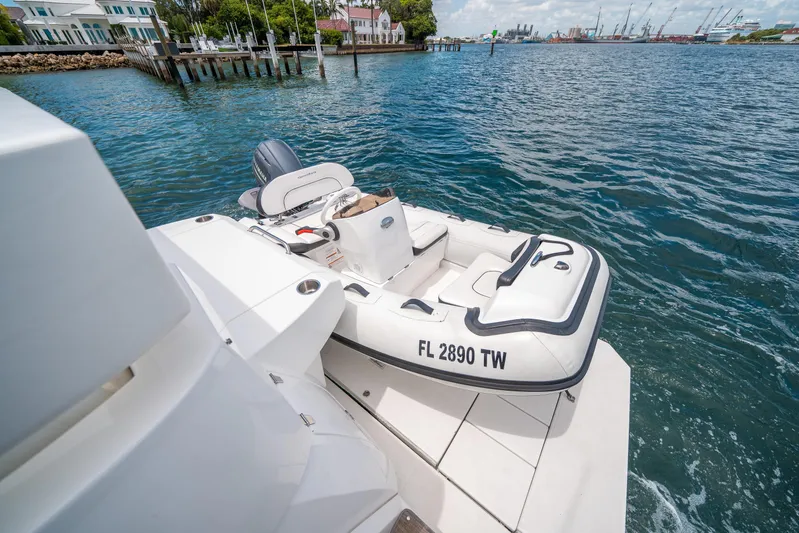 Risky Business Yacht Photos Pics 2019 Cruisers Yachts Cantius with inflatable boat on water, dock and buildings in background.