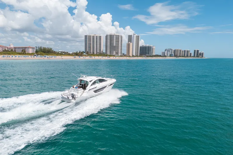 Risky Business Yacht Photos Pics 2019 Cruisers Yachts Cantius cruising near a coastal city skyline under a clear blue sky.