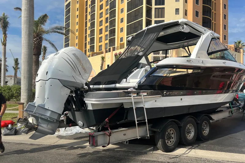  Yacht Photos Pics 2023 Four Winns H350 OB boat on trailer near tall building and palm trees.