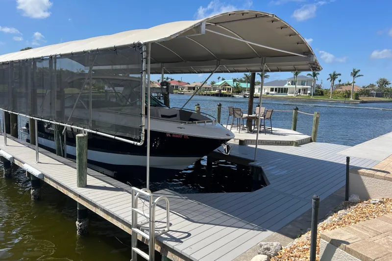  Yacht Photos Pics 2023 Four Winns H350 OB boat docked under canopy on sunny waterfront.