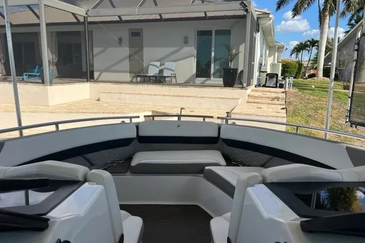  Yacht Photos Pics 2023 Four Winns H350 OB boat interior with seating, docked near a modern house.