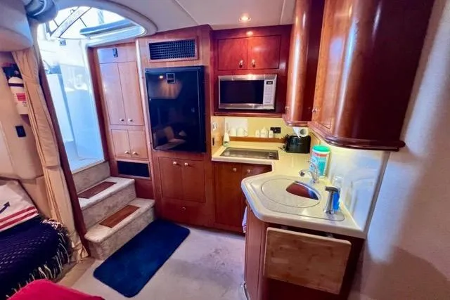 Partner Ship Yacht Photos Pics 2003 Cruisers Yachts 3772 Express interior with kitchenette, microwave, and wooden cabinetry.
