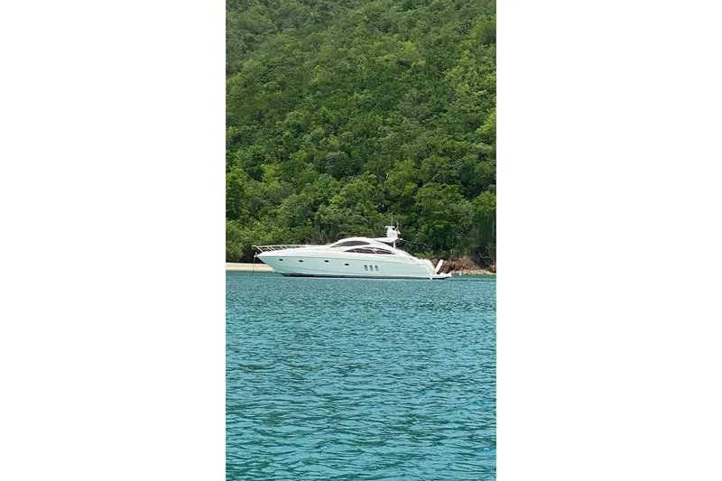 Relentless Yacht Photos Pics 2009 Sunseeker Predator 62 yacht anchored near lush green coastline.