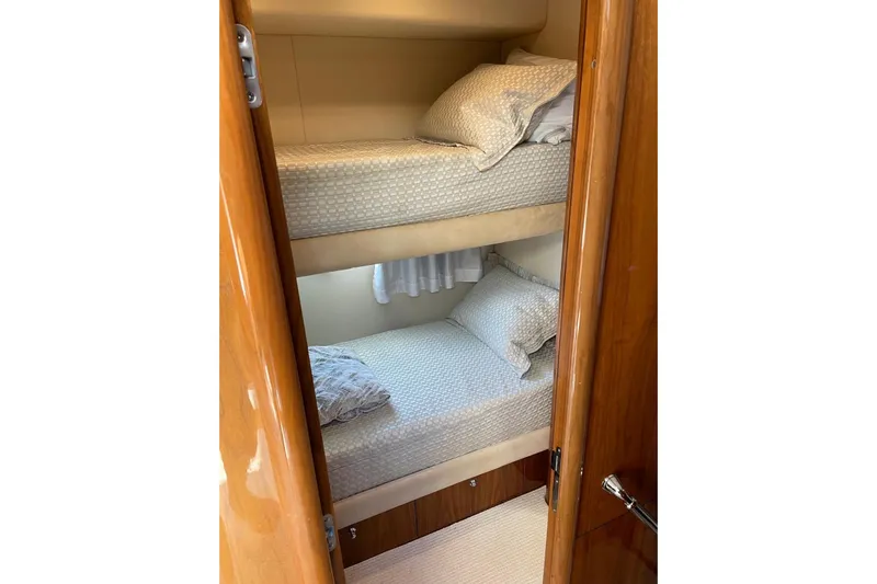 Relentless Yacht Photos Pics Bunk beds in 2009 Sunseeker Predator 62 yacht cabin, featuring wooden finishes and cozy bedding.