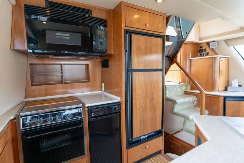 Candykiss Yacht Photos Pics 2003 Meridian 490 Pilothouse kitchen with wood cabinetry, stove, microwave, and stairs.