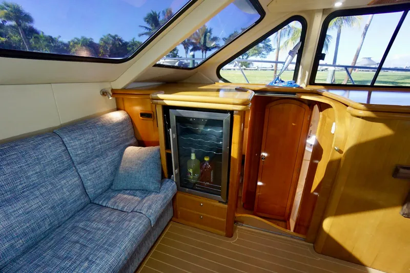 Fifth Day Yacht Photos Pics Interior of 2000 Venturer 44 yacht with sofa, mini fridge, and wooden cabinetry.