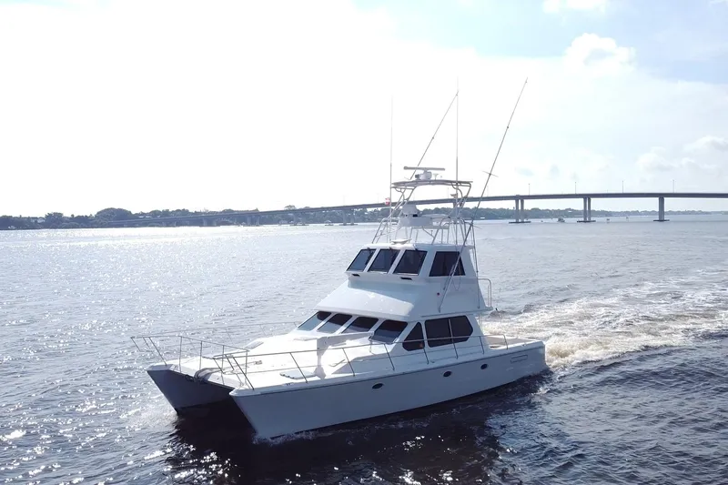 Fifth Day Yacht Photos Pics Luxurious 2000 Voyager 44 yacht cruising on a sunny day near a bridge.