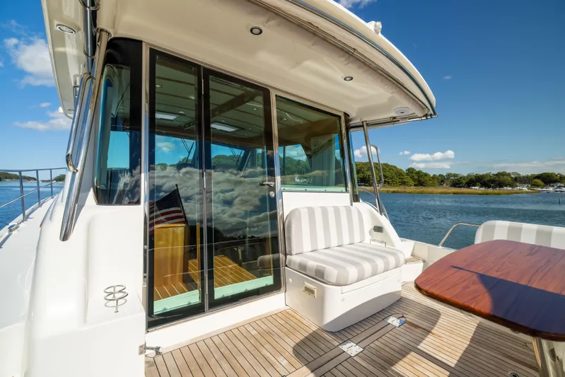  Yacht Photos Pics 2022 Sabre 48 Salon Express yacht deck with seating and table, overlooking serene water.