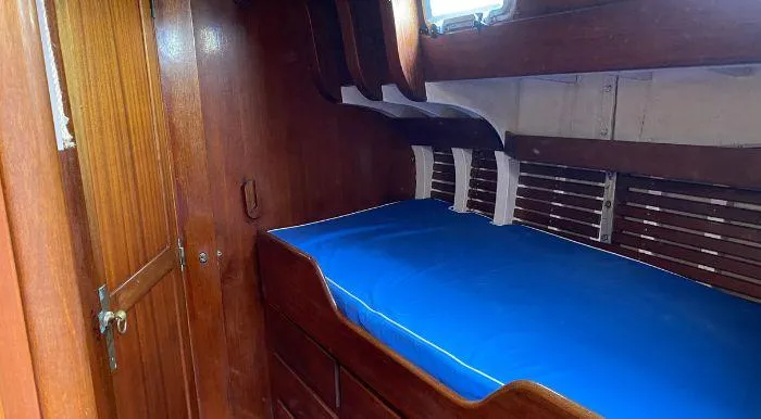 Interior cabin of 1968 Raymond Labbé Shipyard Classic Sloop with wooden finish and blue bedding.