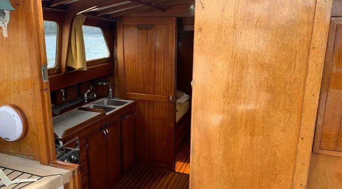 Interior of 1968 Raymond Labbé Classic Sloop with wooden cabinetry and compact kitchen area.