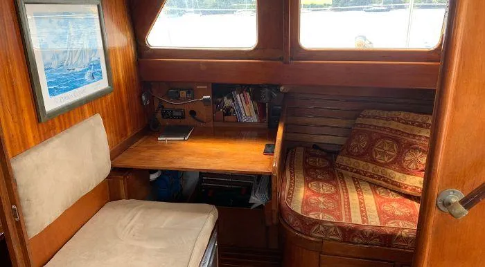 Cozy interior of 1968 Raymond Labbé Shipyard Classic Sloop with wooden desk and seating area.