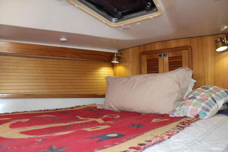 Cuckoo's Nest II Yacht Photos Pics Cozy cabin interior of 2002 Catalina MkII sailboat with wooden accents and nautical-themed bedding.