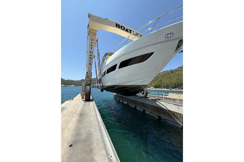  Yacht Photos Pics 2020 Princess Y78 yacht being lifted at a marina with clear blue water.