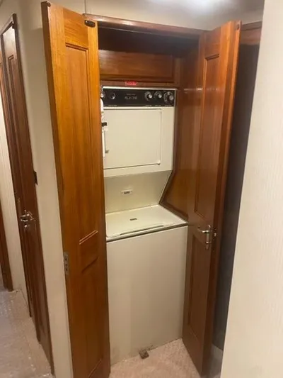 Dry-hydro Yacht Photos Pics 1990 Viking Convertible laundry area with stacked washer and dryer behind wooden doors.