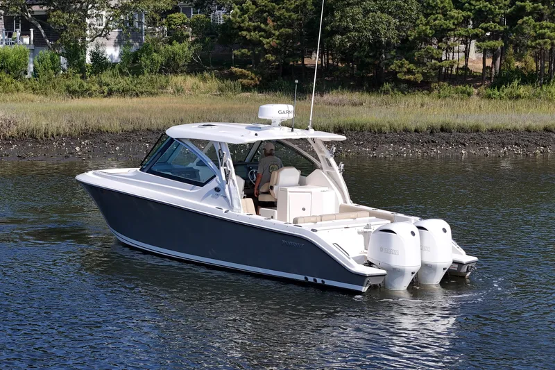  Yacht Photos Pics 2018 Pursuit DC 295 Dual Console boat cruising on a calm river near a wooded shoreline.