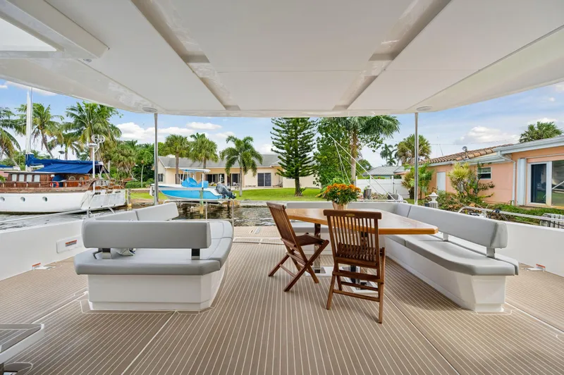 Euphoria Yacht Photos Pics Spacious deck of 2024 Leopard 53 Powercat with seating and table, docked by waterfront homes.