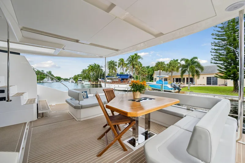 Euphoria Yacht Photos Pics Leopard 53 Powercat 2024 yacht deck with seating and table, docked by waterfront homes.
