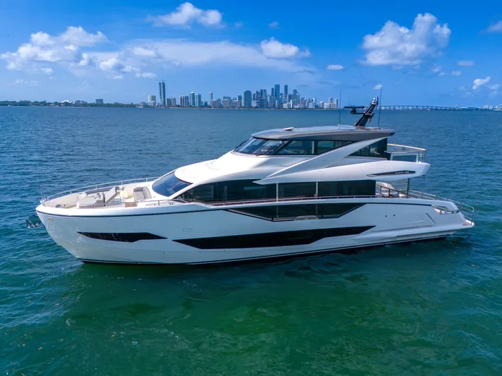Worth The Wait Yacht Photos Pics 2024 Sunseeker Ocean 182 yacht cruising on blue ocean with city skyline backdrop.