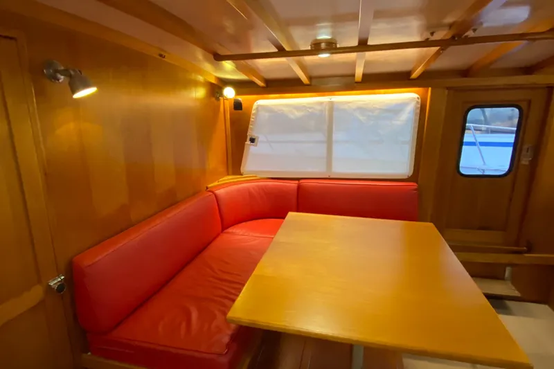 Lord Stanley Yacht Photos Pics 1988 Lyman-Morse Jarvis Newman Cruiser interior with red seating and wooden table.
