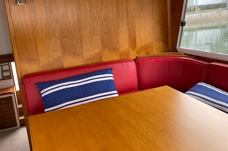Lord Stanley Yacht Photos Pics 1988 Lyman-Morse Jarvis Newman cruiser interior with red seating, wooden table, and striped cushions.