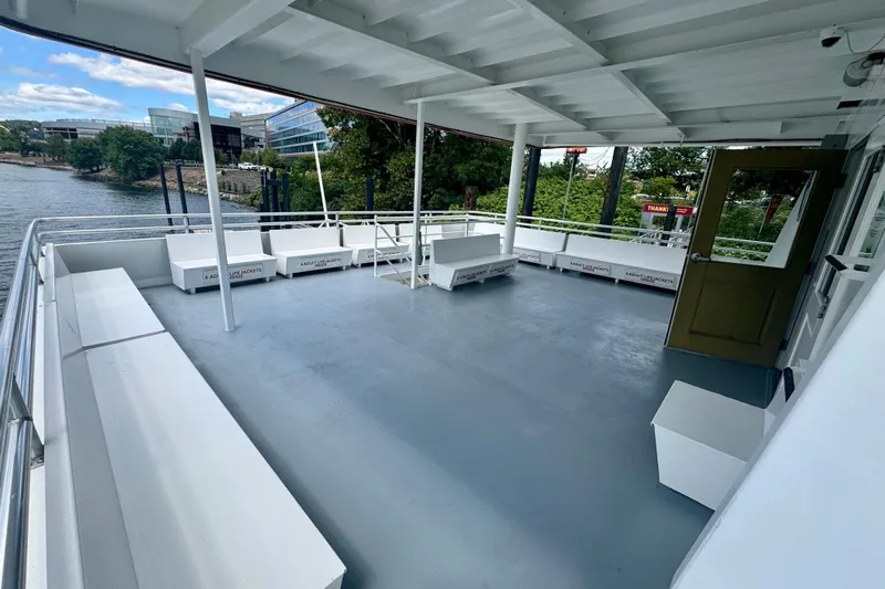 M/v Explorer Yacht Photos Pics Spacious deck of a 2016 Custom Commercial Research Riverboat, docked by a scenic riverside.