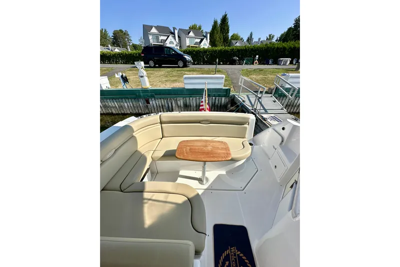 Carpe Diem Yacht Photos Pics 2015 Rinker 340 Express Cruiser with beige seating and wooden table, docked near a house.