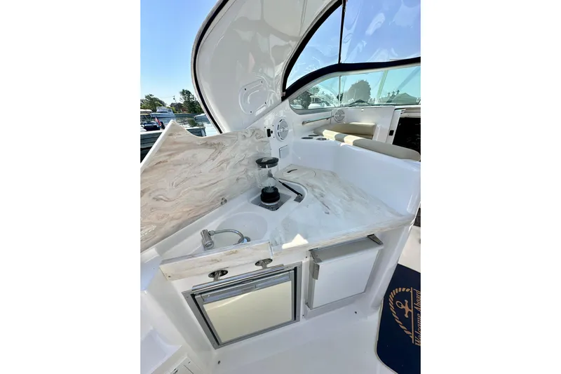 Carpe Diem Yacht Photos Pics 2015 Rinker 340 Express Cruiser interior with kitchenette, featuring sink and storage cabinets.