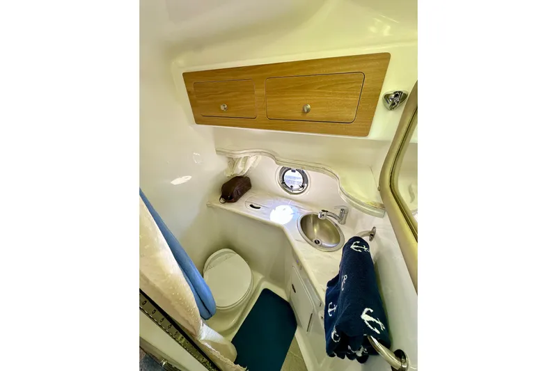 Carpe Diem Yacht Photos Pics 2015 Rinker 340 Express Cruiser bathroom with sink, toilet, and wooden cabinets.