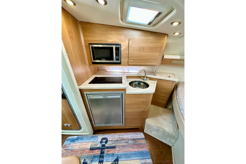 Carpe Diem Yacht Photos Pics 2015 Rinker 340 Express Cruiser interior kitchen with microwave, sink, and compact fridge.