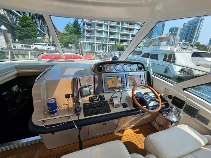 Wrist Shot Yacht Photos Pics 2005 Sea Ray 48 Sundancer helm with navigation equipment, wooden steering wheel, and marina view.