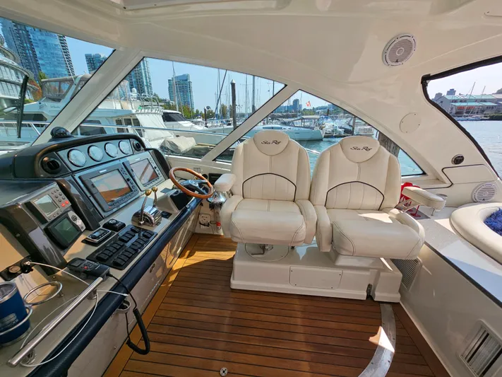 Wrist Shot Yacht Photos Pics 2005 Sea Ray 48 Sundancer helm with dual seats, wooden flooring, and marina view.