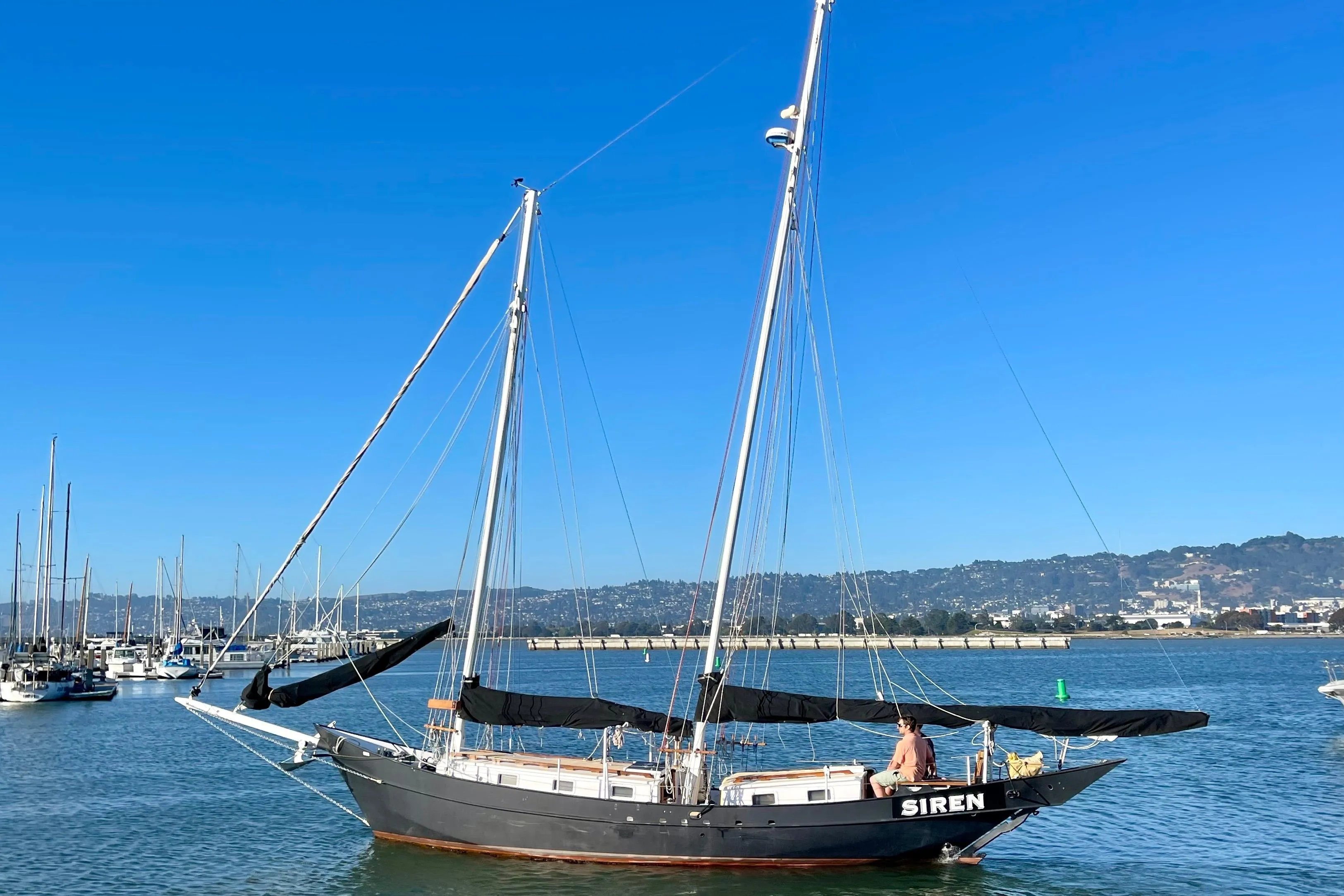 Sailboat "Siren" on calm waters, Pinky Custom 2008 model, under clear blue sky.