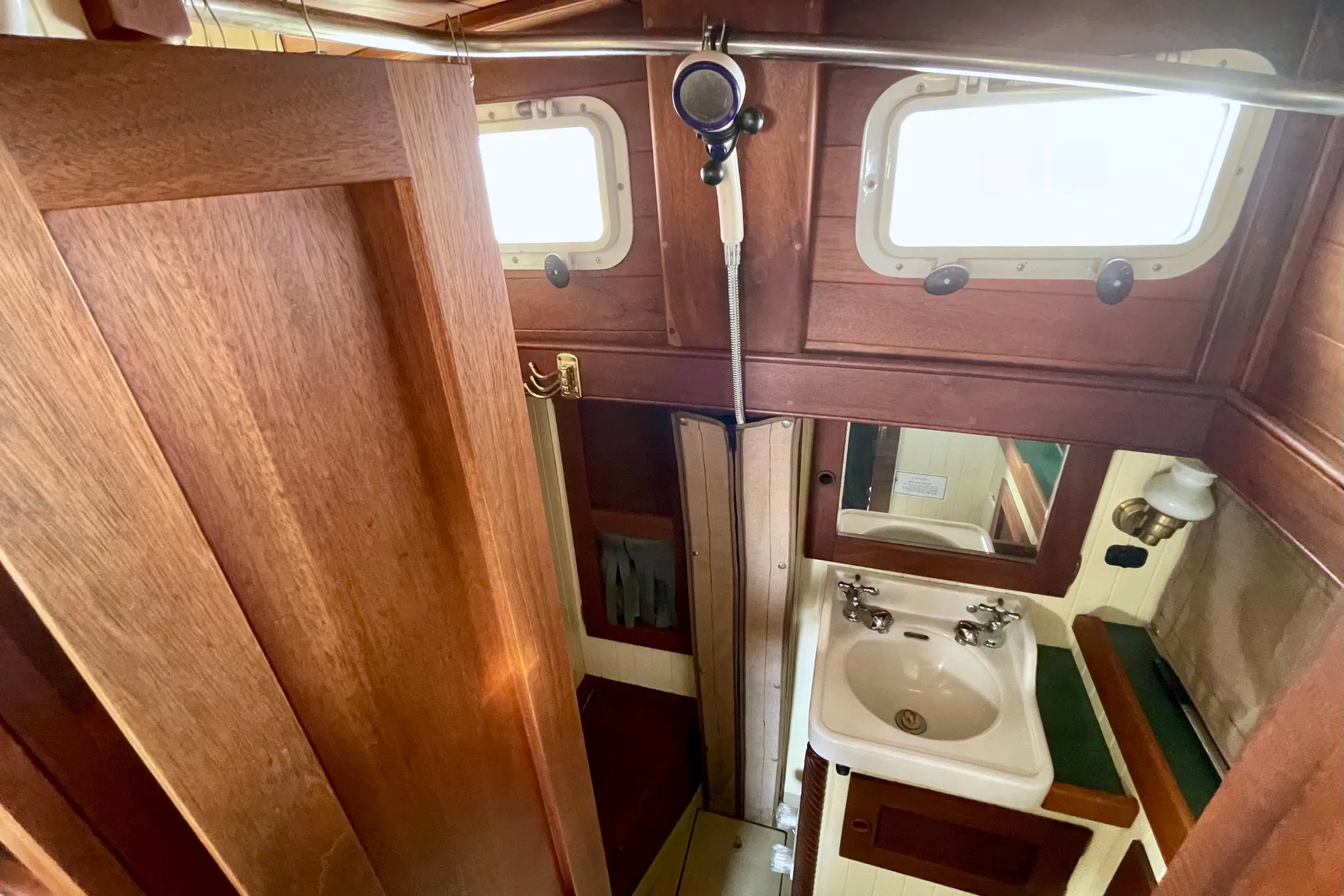 Compact wooden boat bathroom with sink, mirror, and shower in 2008 Pinky Custom model.