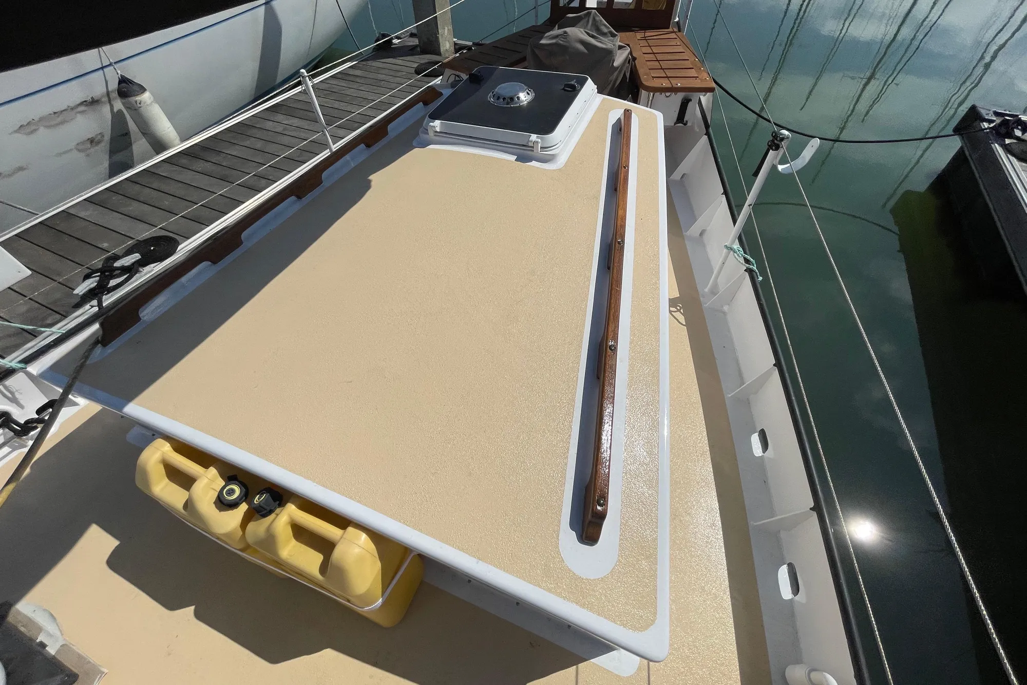Deck of 2008 Pinky Custom boat with wooden rail and yellow containers.