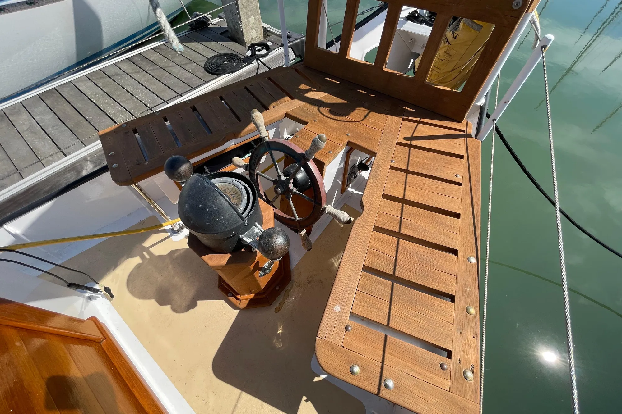 Wooden deck of 2008 Pinky Custom boat with steering wheel and compass.