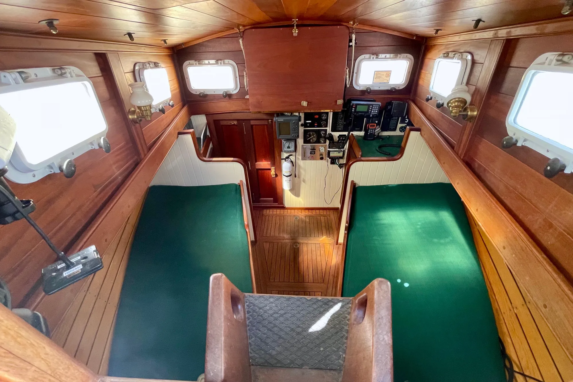 Interior of 2008 Pinky Custom boat with wooden paneling and green seating.