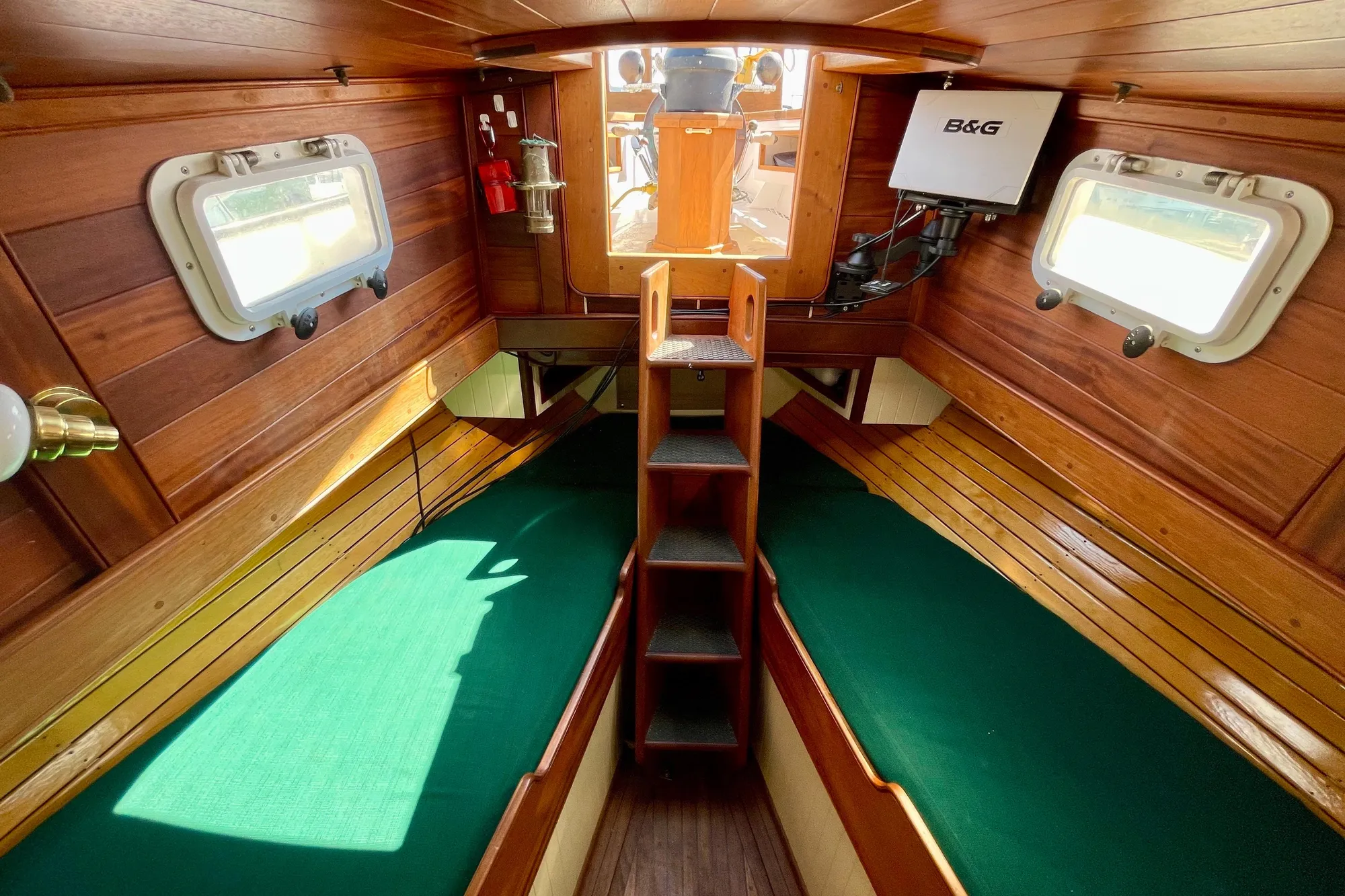 Cozy 2008 Pinky Custom boat cabin with wooden interior and green cushions.