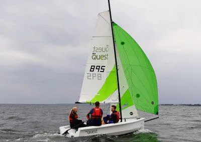 2023 RS Quest sailboat with green sail on open water.