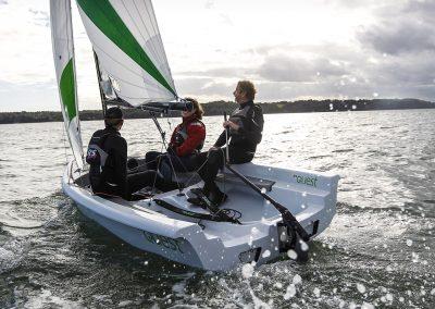 2023 RS Quest sailboat with three people sailing on a lake.