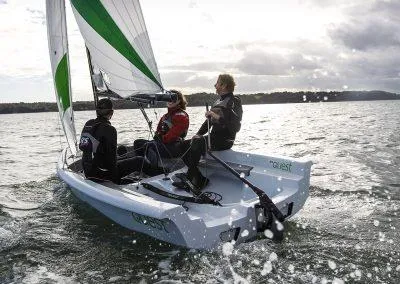 2023 RS Quest sailboat with three people sailing on a lake.
