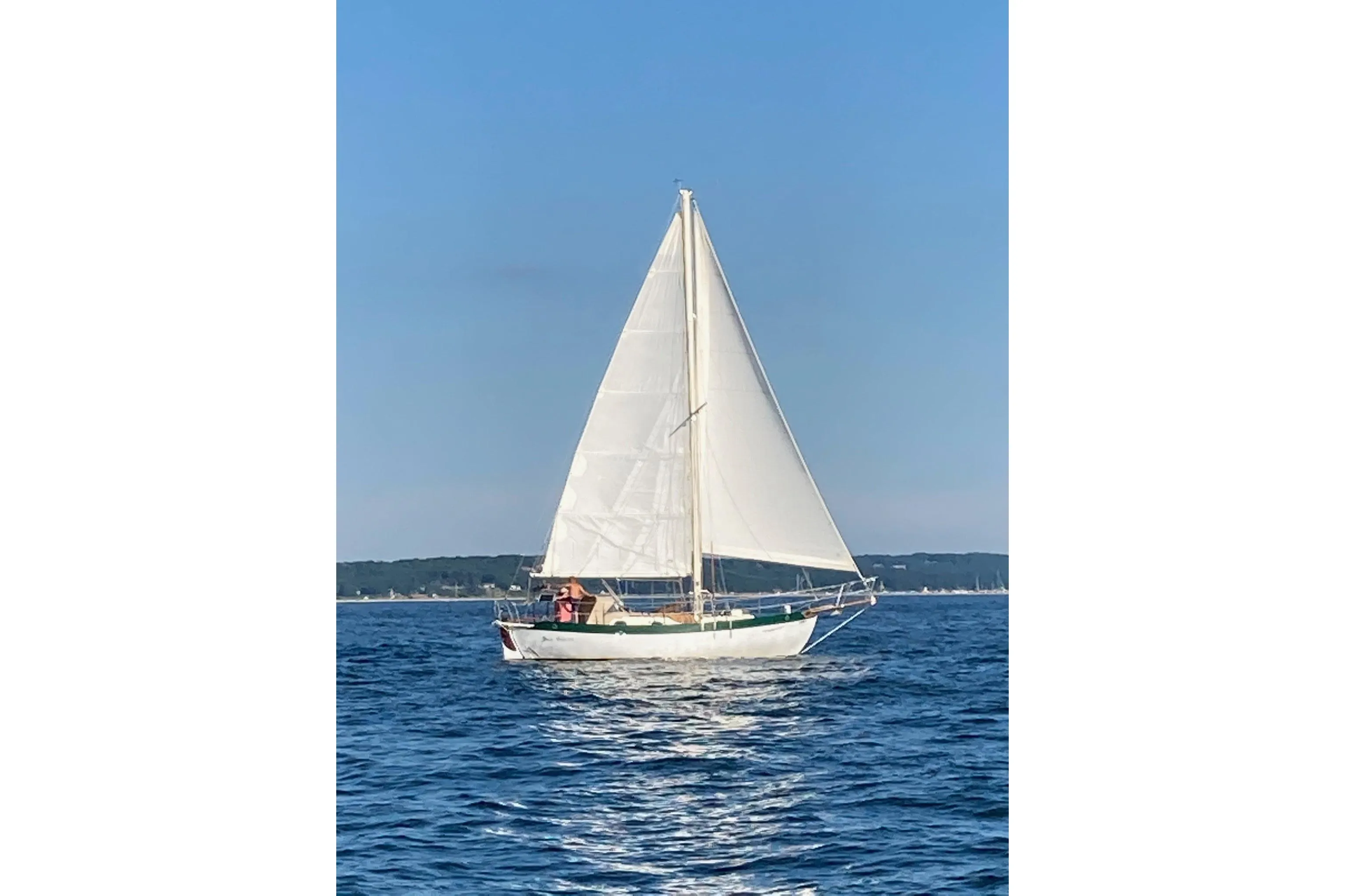 1977 Westsail Cutter sailboat cruising on open water under clear blue skies.