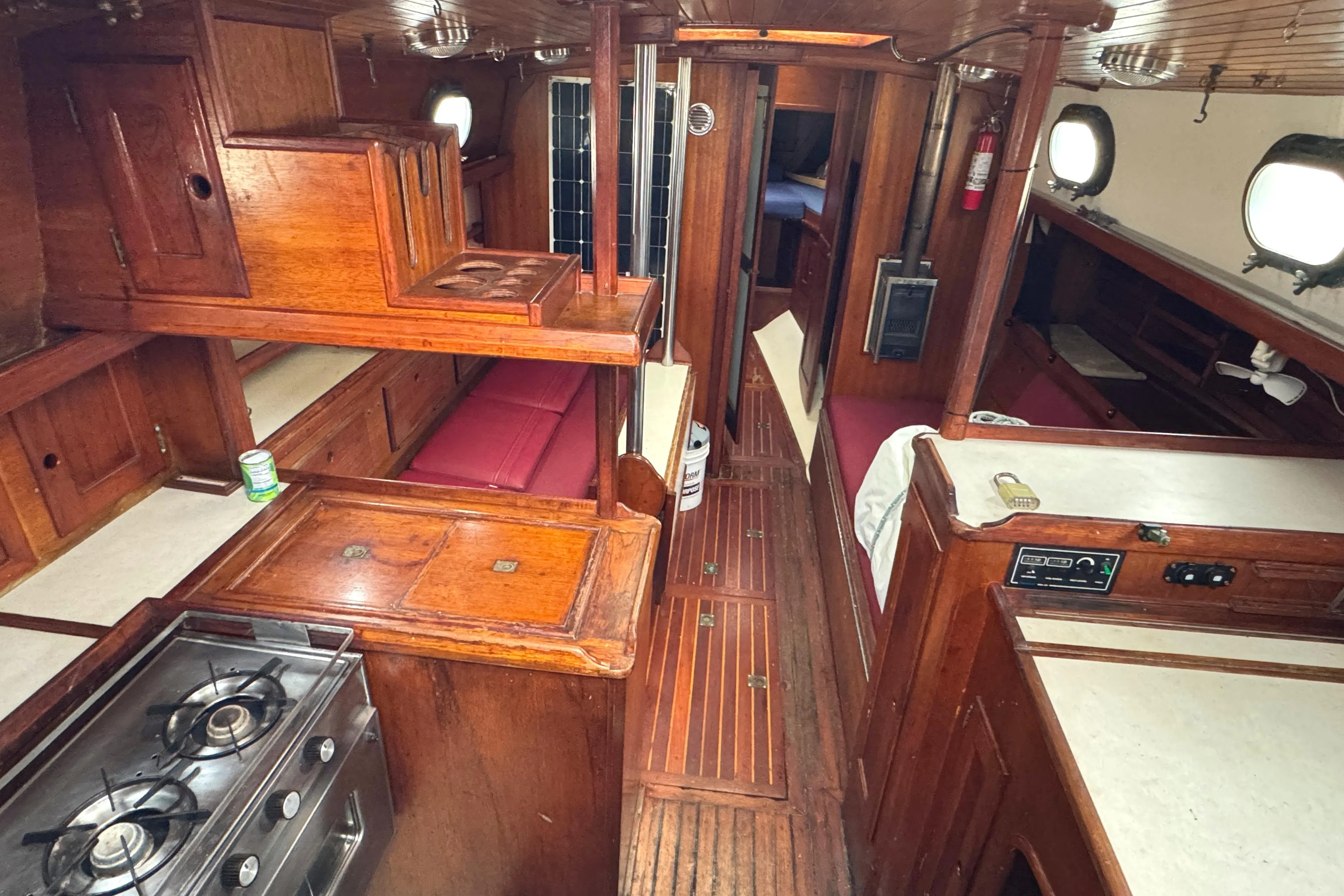 1977 Westsail Cutter interior with wooden cabinetry, galley, and seating area.