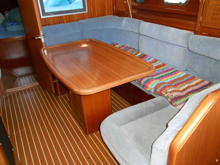 Pilitak Yacht Photos Pics Interior of 2001 Bavaria 37 yacht with wooden table and cushioned seating.