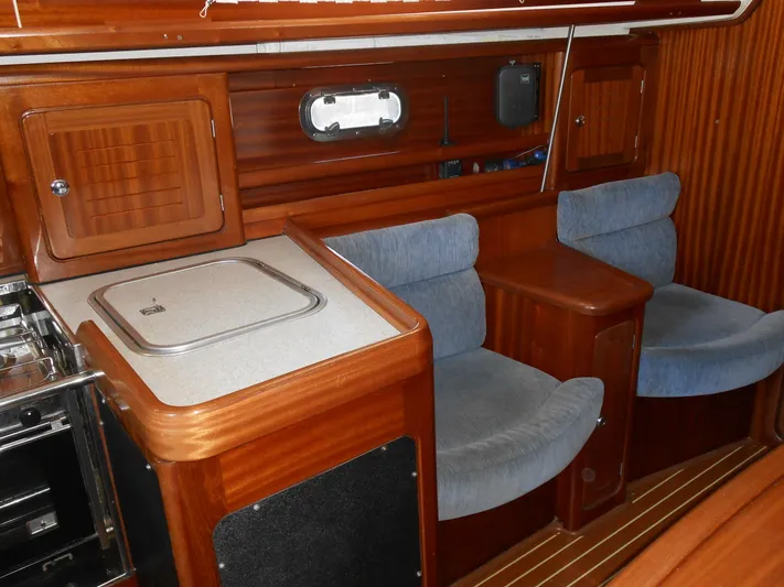 Pilitak Yacht Photos Pics Interior of 2001 Bavaria 37 yacht with wooden cabinetry and blue cushioned seating.