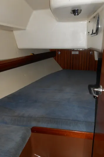 Pilitak Yacht Photos Pics Cabin interior of 2001 Bavaria 37 sailboat with blue bedding and wooden accents.