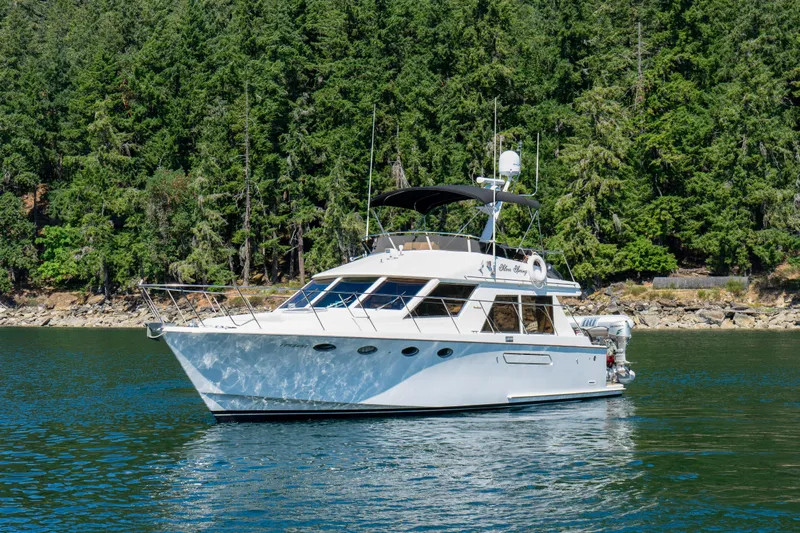 Silver Spring Yacht Photos Pics 1985 Ocean Alexander 420 Sport Sedan yacht on calm water, surrounded by lush forest.