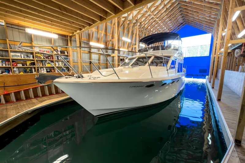 Silver Spring Yacht Photos Pics 1985 Ocean Alexander 420 Sport Sedan in a wooden boathouse, reflecting on calm water.