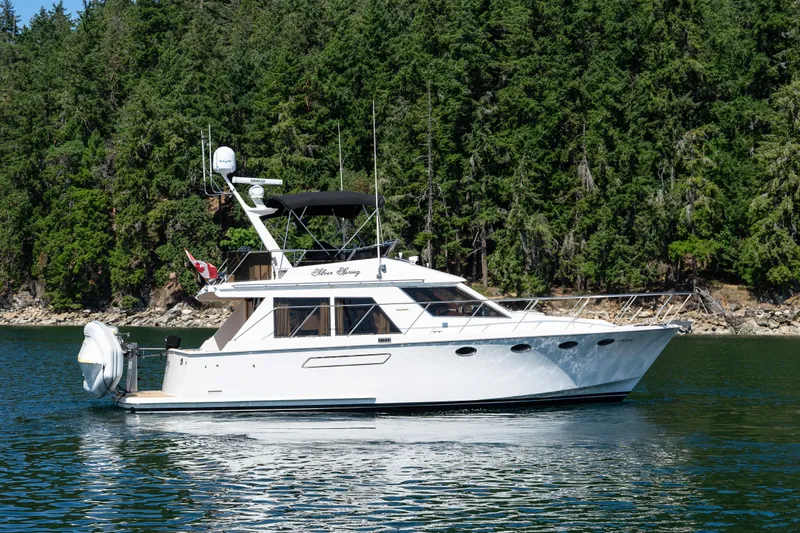 Silver Spring Yacht Photos Pics 1985 Ocean Alexander 420 Sport Sedan yacht cruising near lush forested shoreline.