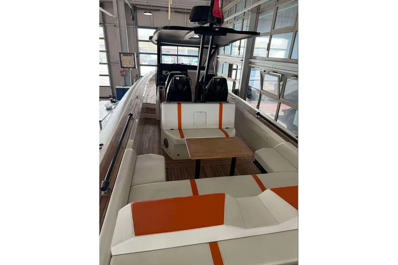  Yacht Photos Pics 2023 Technohull Omega 47 boat interior with orange-accented seating and wooden table.