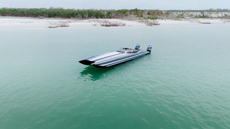 Yacht Photos Pics 2024 MTI 440X powerboat on calm turquoise water near a sandy shoreline.